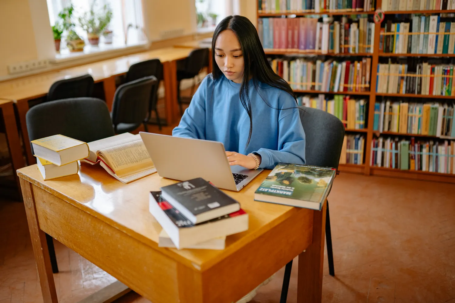 College student using a silver laptop in a library